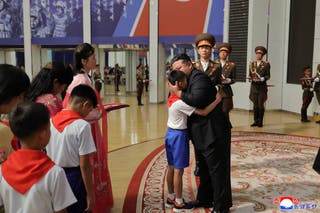 North Korean leader Kim Jong Un embracing a family member of a soldier who participated in overseas military operations, in Pyongyang